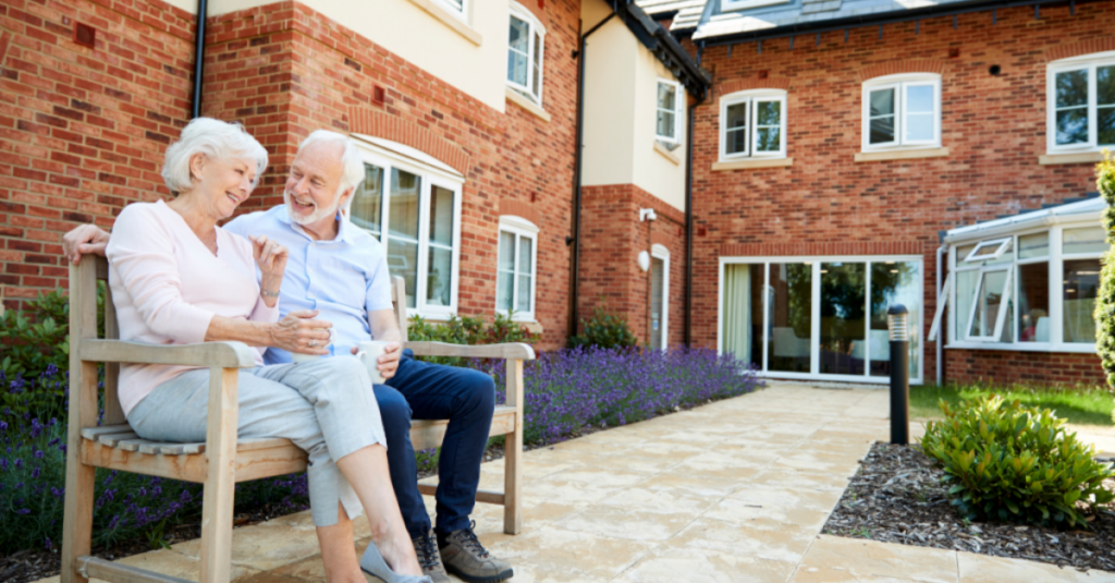 older couple sitting on a bench at an assisted living facility